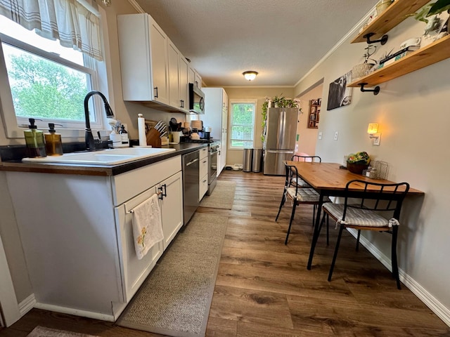 2728 Pine Ave, Slayton, MN 56172 - kitchen with stainless steel appliances, a sink, dark wood-style flooring, white cabinetry, and ornamental molding