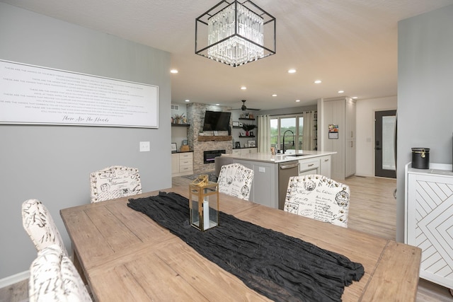 907 Rodeo Dr SE, Pine Island, MN 55963 - dining space with a fireplace, ceiling fan, recessed lighting, light wood finished floors, and a chandelier