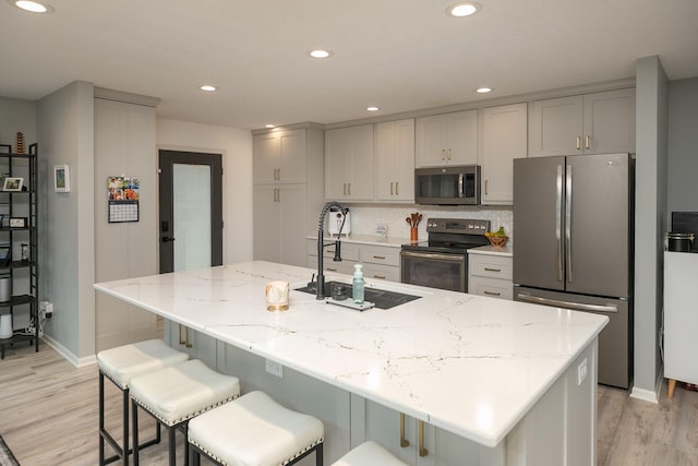 907 Rodeo Dr SE, Pine Island, MN 55963 - kitchen featuring stainless steel appliances, a sink, baseboards, light wood finished floors, and light stone countertops