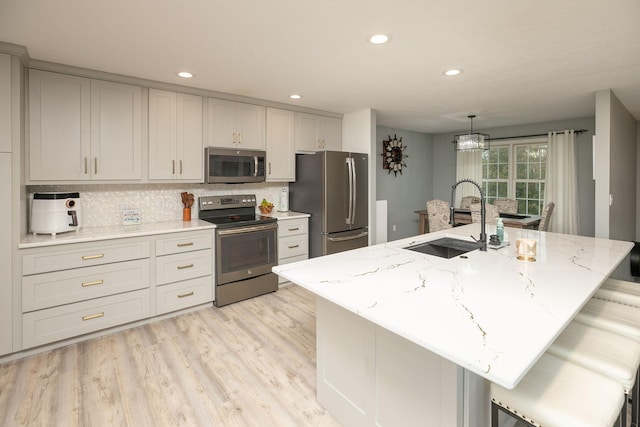 907 Rodeo Dr SE, Pine Island, MN 55963 - kitchen with stainless steel appliances, a sink, backsplash, light wood-style flooring, and light stone counters
