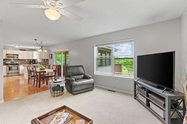 27385 Millicent Ln, Chisago Lake Twp, MN 55013 - living room with light carpet, a chandelier, baseboards, and a ceiling fan