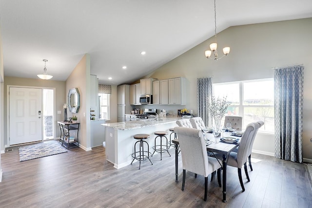 dining room with baseboards, wood finished floors, a chandelier, high vaulted ceiling, and recessed lighting