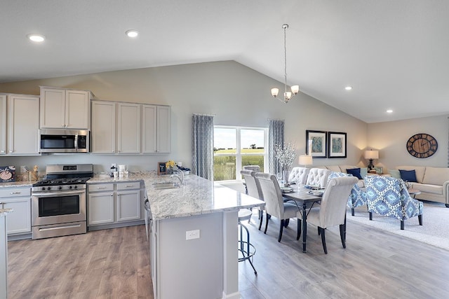 kitchen with stainless steel appliances, a peninsula, a sink, open floor plan, and a kitchen breakfast bar