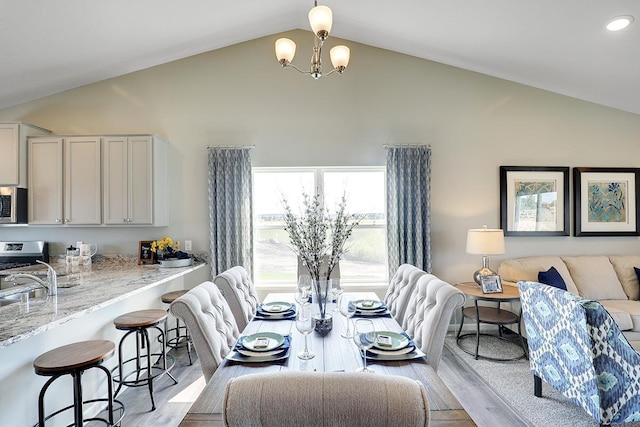 dining room with wood finished floors, high vaulted ceiling, recessed lighting, and a chandelier