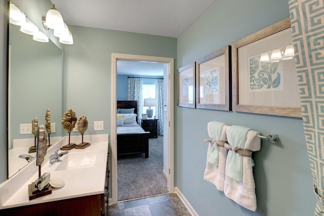 bathroom with connected bathroom, double vanity, and a textured ceiling