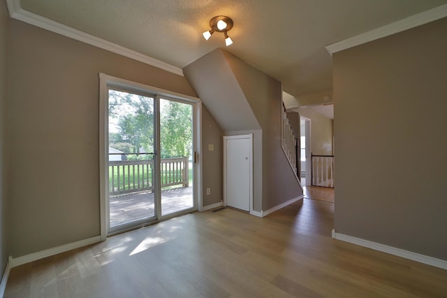 809 7th St, Brainerd, MN 56401 - unfurnished living room with light wood finished floors, baseboards, ornamental molding, vaulted ceiling, and a textured ceiling