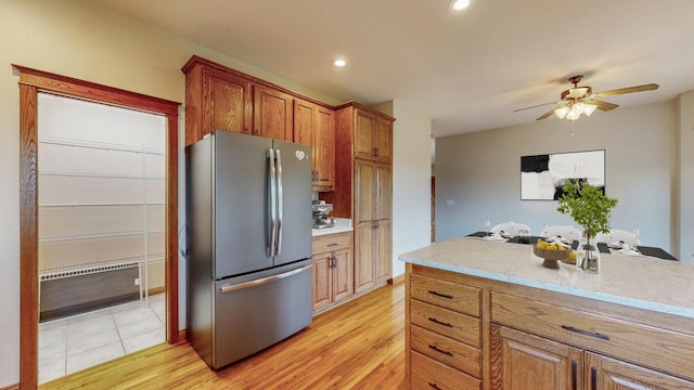 kitchen with freestanding refrigerator, light countertops, brown cabinets, a ceiling fan, and recessed lighting