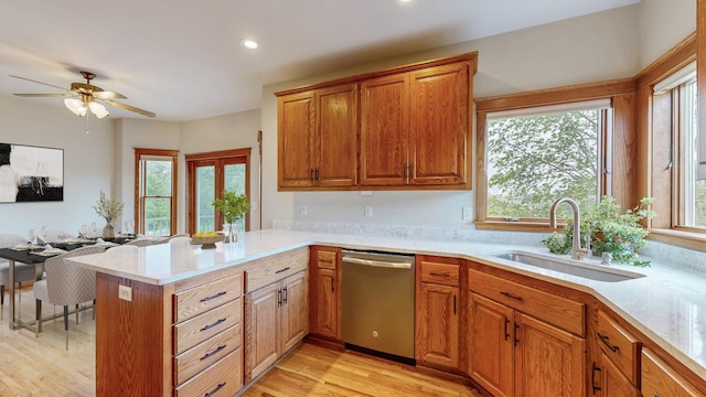 kitchen featuring stainless steel dishwasher, a sink, light countertops, a peninsula, and ceiling fan