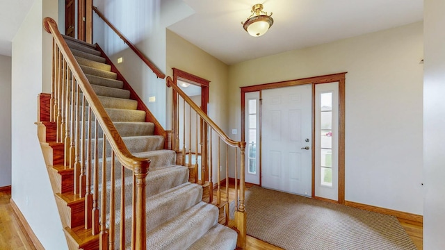 foyer entrance featuring wood finished floors, stairs, and baseboards