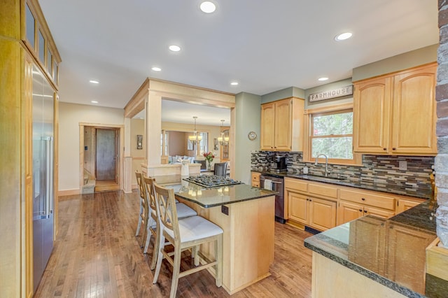 8632 Neal Ave S, Denmark Twp, MN 55033 - kitchen with a sink, appliances with stainless steel finishes, a breakfast bar, dark stone countertops, and light brown cabinets