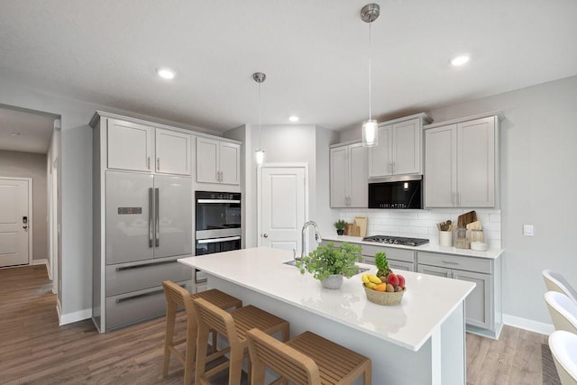 8397 Brumby Trl, Woodbury, MN 55129 - kitchen with appliances with stainless steel finishes, tasteful backsplash, light wood finished floors, baseboards, and recessed lighting