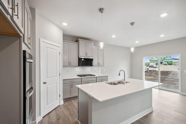 8397 Brumby Trl, Woodbury, MN 55129 - kitchen with gray cabinetry, a sink, light wood-style floors, decorative backsplash, and recessed lighting