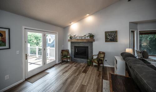 2211 Douglynn Ln, Saint Paul, MN 55119 - living room featuring lofted ceiling, a glass covered fireplace, wood finished floors, and baseboards