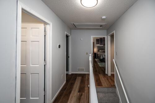2211 Douglynn Ln, Saint Paul, MN 55119 - hallway featuring attic access, dark wood finished floors, a textured ceiling, and baseboards