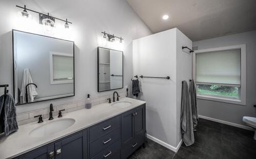 2211 Douglynn Ln, Saint Paul, MN 55119 - bathroom with double vanity, toilet, baseboards, tile patterned flooring, and vaulted ceiling