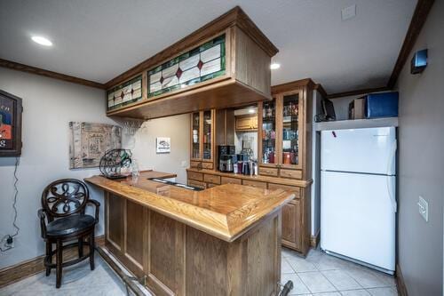 2211 Douglynn Ln, Saint Paul, MN 55119 - bar featuring freestanding refrigerator, black electric stovetop, light tile patterned flooring, crown molding, and baseboards