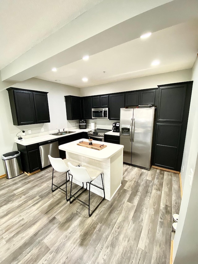 kitchen featuring stainless steel appliances, dark cabinets, light wood finished floors, light countertops, and recessed lighting