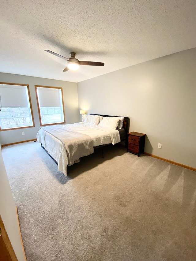 carpeted bedroom with baseboards, a textured ceiling, and a ceiling fan