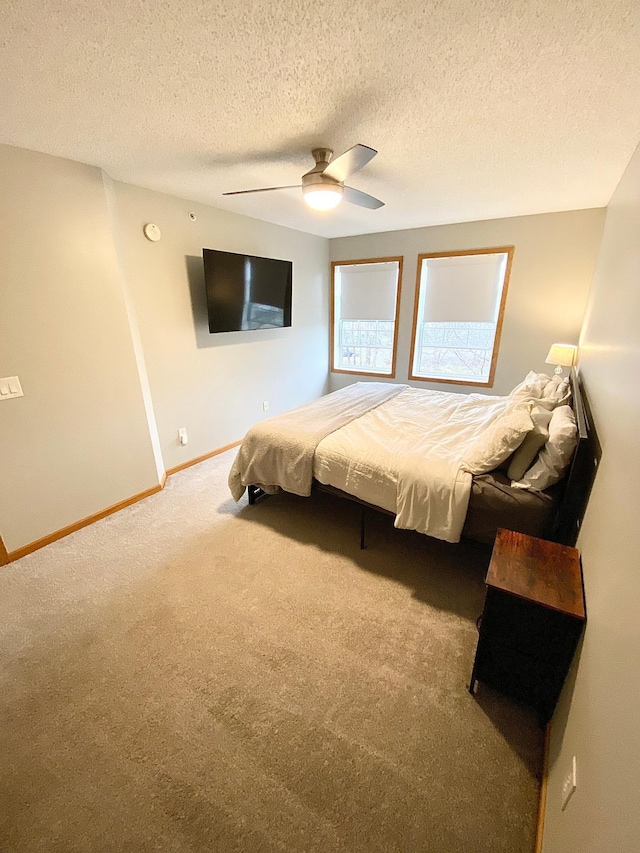 bedroom with carpet flooring, baseboards, a ceiling fan, and a textured ceiling