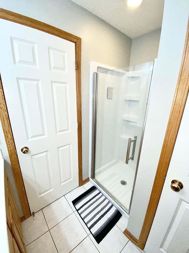 bathroom with a stall shower, tile patterned flooring, and a textured ceiling