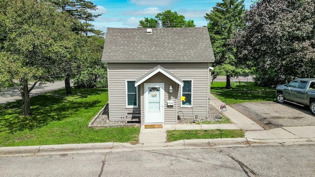 view of front of house featuring a shingled roof and a front yard