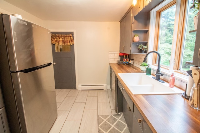 kitchen with freestanding refrigerator, a baseboard radiator, a sink, and butcher block counters