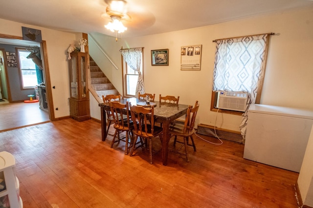 dining room featuring stairs, a ceiling fan, light wood-type flooring, and cooling unit