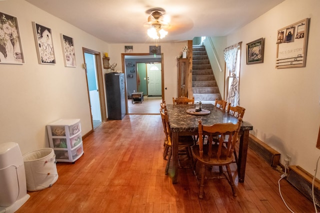 dining space with light wood-style flooring, stairway, a ceiling fan, and baseboards