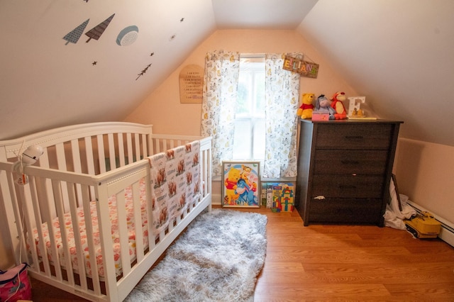 bedroom with wood finished floors, vaulted ceiling, and a nursery area