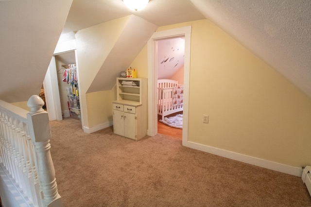 additional living space featuring light carpet, lofted ceiling, baseboards, a baseboard radiator, and a textured ceiling