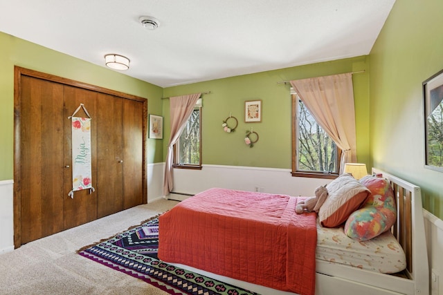 7012 Sally Ln, Edina, MN 55439 - carpeted bedroom featuring multiple windows, a baseboard radiator, a closet, and a wainscoted wall