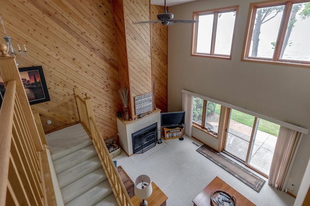 8012 Par Five Dr, South Harbor Twp, MN 56359 - living room featuring carpet flooring, a towering ceiling, a glass covered fireplace, ceiling fan, and wood walls