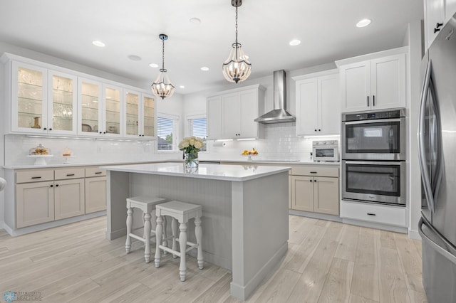 508 13th St NE, Dilworth, MN 56529 - kitchen with wall chimney exhaust hood, appliances with stainless steel finishes, a chandelier, a kitchen island, and decorative backsplash