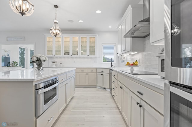 508 13th St NE, Dilworth, MN 56529 - kitchen featuring wall chimney exhaust hood, a chandelier, black electric cooktop, double oven, and light wood-type flooring