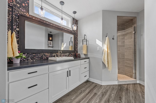 508 13th St NE, Dilworth, MN 56529 - bathroom with vanity, wood finished floors, baseboards, and tiled shower