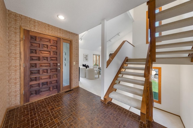 foyer entrance with wallpapered walls, stairway, and baseboards