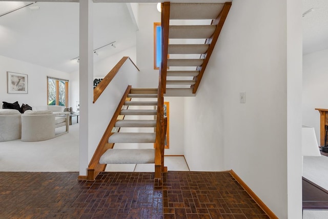stairs featuring rail lighting and baseboards