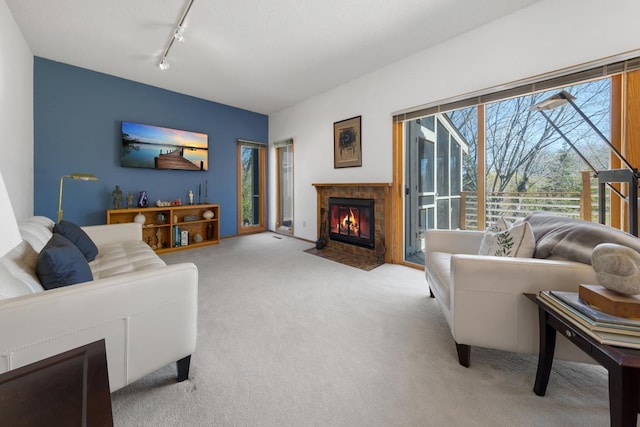 living room with carpet flooring, rail lighting, and a tiled fireplace