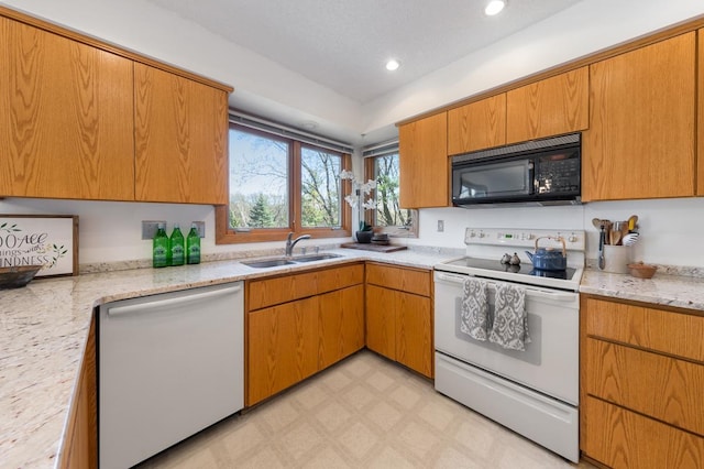 kitchen with white appliances, a sink, light floors, recessed lighting, and light stone counters