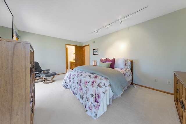 bedroom featuring light carpet, rail lighting, and baseboards