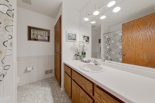 bathroom with vanity, tile walls, toilet, wainscoting, and a shower with shower curtain