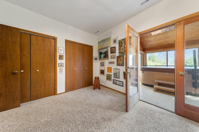 bedroom with french doors, light carpet, multiple closets, and baseboards