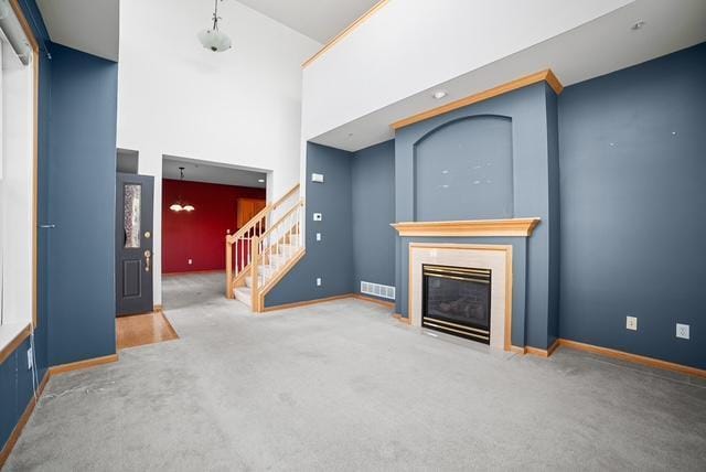 11353 Fergus St NE Unit A, Blaine, MN 55449 - unfurnished living room with stairway, carpet flooring, a fireplace with flush hearth, baseboards, and a towering ceiling