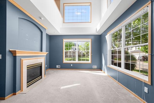 11353 Fergus St NE Unit A, Blaine, MN 55449 - unfurnished living room with carpet flooring, a glass covered fireplace, and baseboards