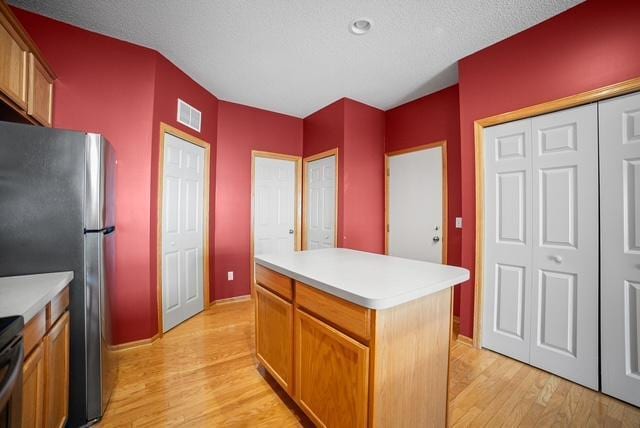 11353 Fergus St NE Unit A, Blaine, MN 55449 - kitchen with light wood-style flooring, light countertops, a kitchen island, and brown cabinetry