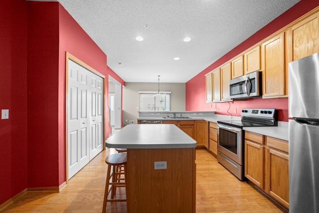 11353 Fergus St NE Unit A, Blaine, MN 55449 - kitchen featuring stainless steel appliances, light wood finished floors, a breakfast bar area, light countertops, and recessed lighting