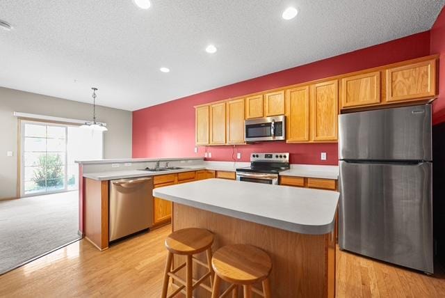 11353 Fergus St NE Unit A, Blaine, MN 55449 - kitchen with stainless steel appliances, a peninsula, light countertops, light wood-style flooring, and a center island