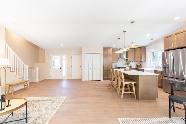 8464 Greenwood Dr, Mounds View, MN 55112 - kitchen with stainless steel fridge, a breakfast bar, a center island, light wood-type flooring, and light countertops