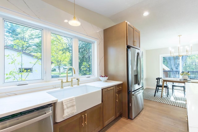 8464 Greenwood Dr, Mounds View, MN 55112 - kitchen with stainless steel appliances, a sink, light wood-type flooring, light stone counters, and a chandelier