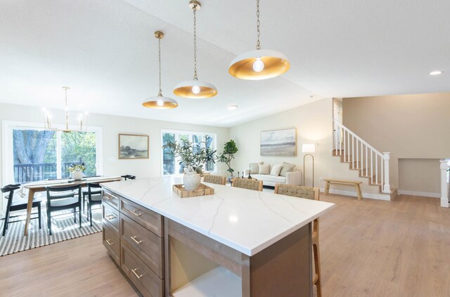 8464 Greenwood Dr, Mounds View, MN 55112 - kitchen with vaulted ceiling, light wood-type flooring, hanging light fixtures, a center island, and light stone counters